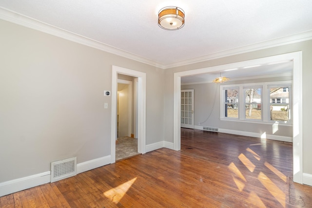 unfurnished room with wood-type flooring, visible vents, baseboards, and ornamental molding