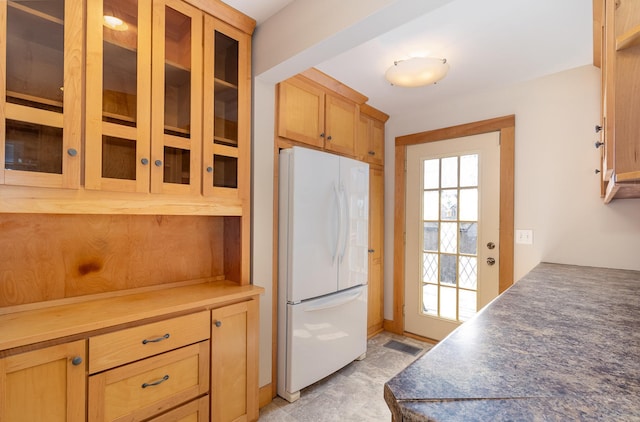 kitchen with visible vents, glass insert cabinets, and freestanding refrigerator