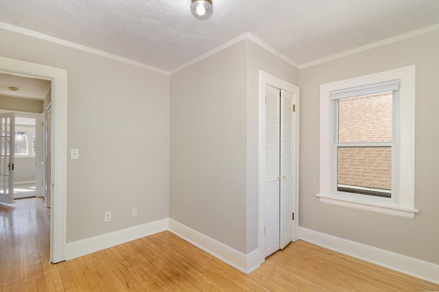 spare room featuring light wood-style floors, baseboards, and ornamental molding