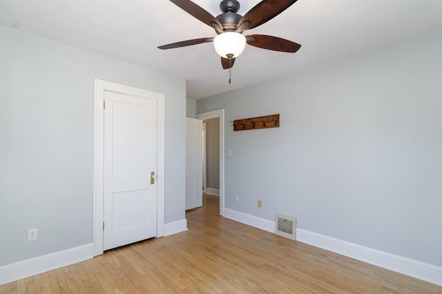 unfurnished bedroom with light wood-style flooring, a ceiling fan, visible vents, and baseboards