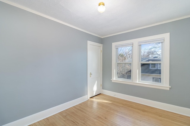 unfurnished room featuring light wood-style floors, a textured ceiling, baseboards, and crown molding