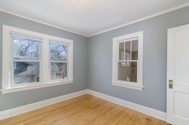 unfurnished room featuring crown molding, light wood finished floors, and baseboards