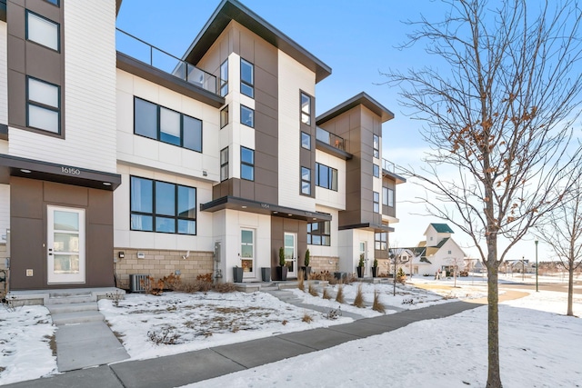 exterior space with stone siding, central air condition unit, and stucco siding