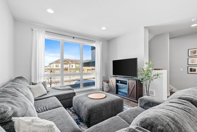 living area with baseboards, wood finished floors, visible vents, and recessed lighting