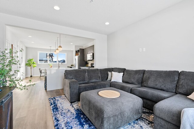 living area with light wood-style floors, recessed lighting, and an inviting chandelier