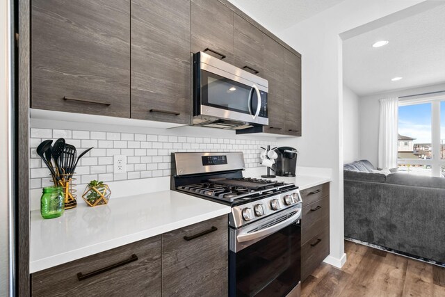 kitchen with stainless steel appliances, dark brown cabinets, and light countertops