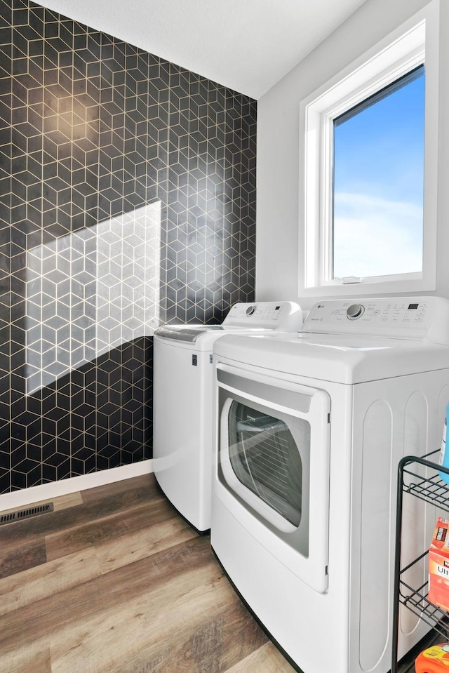 washroom featuring washer and dryer, laundry area, and wood finished floors