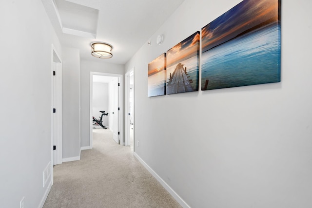 hallway featuring light colored carpet, visible vents, and baseboards