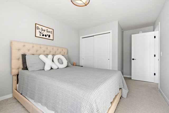 bedroom featuring a closet, light colored carpet, and baseboards