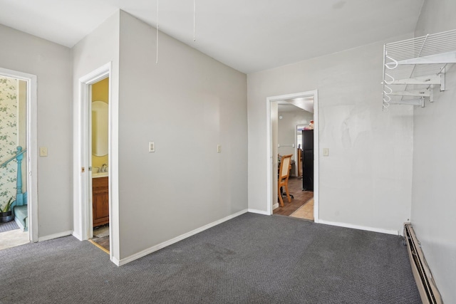 carpeted spare room with a baseboard heating unit