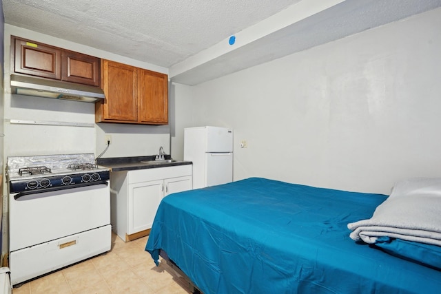 bedroom featuring a textured ceiling, white refrigerator, and sink