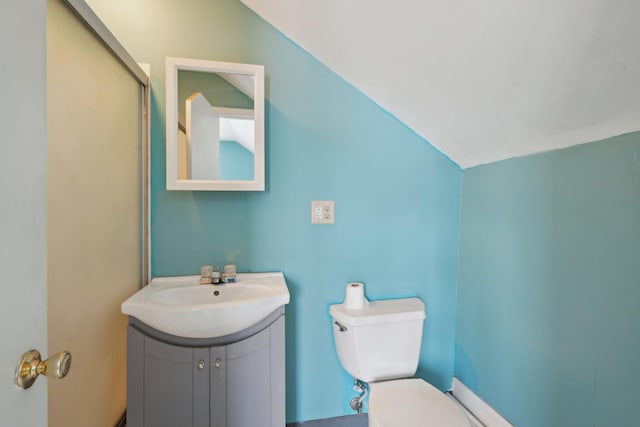 bathroom featuring vanity, toilet, and lofted ceiling