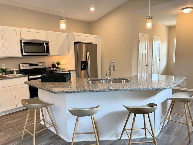 kitchen with sink, dark wood-type flooring, a kitchen island with sink, a breakfast bar, and appliances with stainless steel finishes