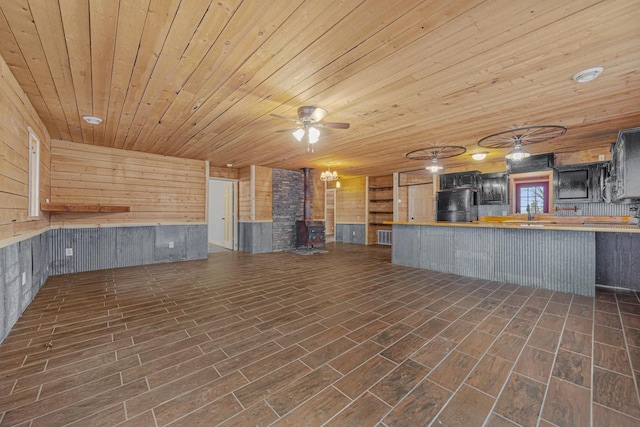 unfurnished living room featuring wood walls, dark hardwood / wood-style flooring, a wood stove, and wooden ceiling