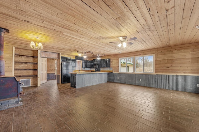 kitchen with dark hardwood / wood-style flooring, butcher block countertops, kitchen peninsula, wooden walls, and black appliances