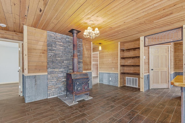 unfurnished living room featuring wood walls, dark hardwood / wood-style flooring, and a wood stove