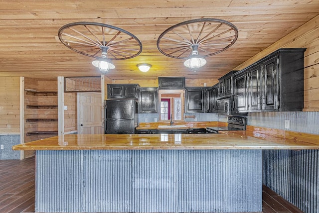 kitchen featuring wood walls, wooden counters, black appliances, dark hardwood / wood-style floors, and kitchen peninsula