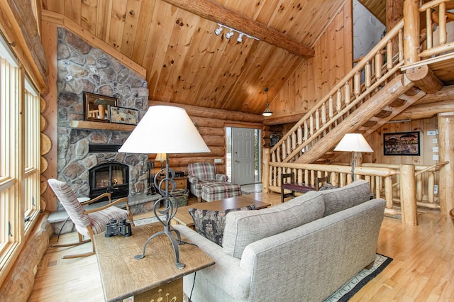 living room featuring wooden ceiling, high vaulted ceiling, a stone fireplace, beam ceiling, and light hardwood / wood-style floors