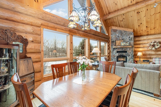 dining area with a fireplace, beam ceiling, light hardwood / wood-style floors, and a wealth of natural light