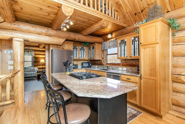 kitchen with black appliances, a kitchen island, light wood-type flooring, and rustic walls