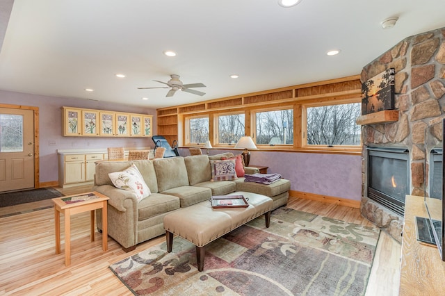 living room featuring a fireplace, light hardwood / wood-style floors, and ceiling fan