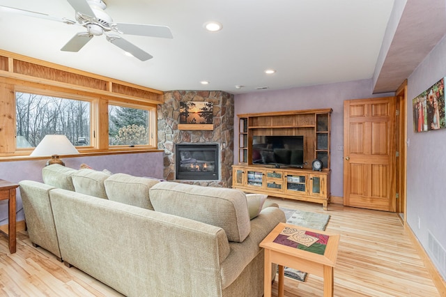 living room with ceiling fan, a fireplace, and light hardwood / wood-style flooring