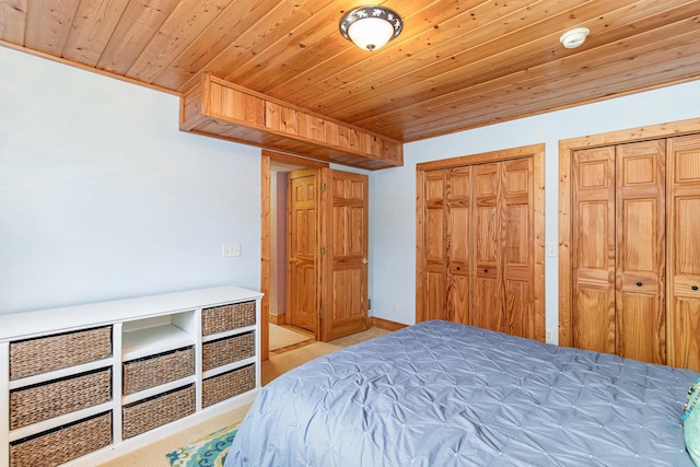 bedroom featuring light carpet, wooden ceiling, and two closets