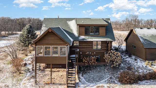 snow covered back of property with a sunroom