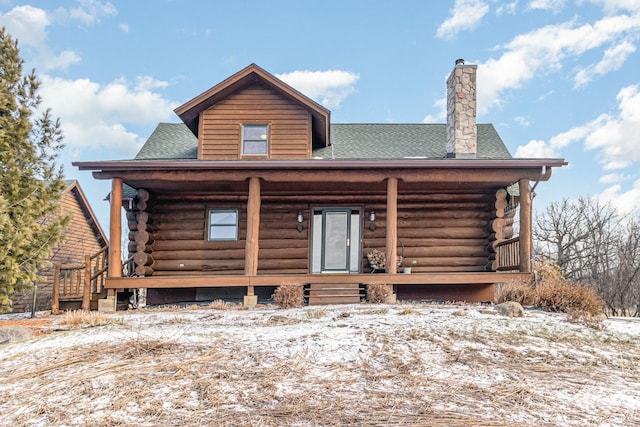 snow covered rear of property with covered porch