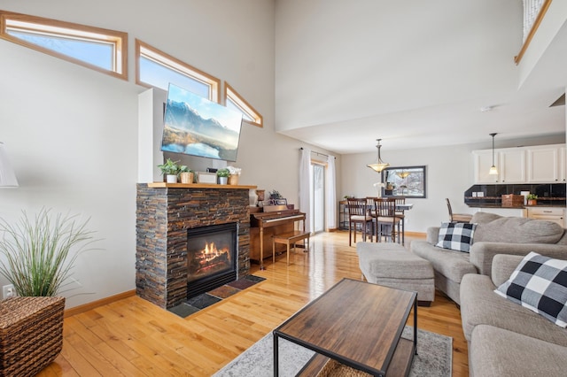 living room with a high ceiling, a fireplace, and light wood-type flooring