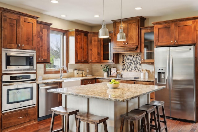 kitchen featuring pendant lighting, a center island, dark hardwood / wood-style floors, appliances with stainless steel finishes, and a breakfast bar area