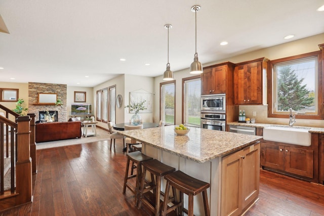 kitchen featuring a fireplace, pendant lighting, stainless steel appliances, and dark hardwood / wood-style floors