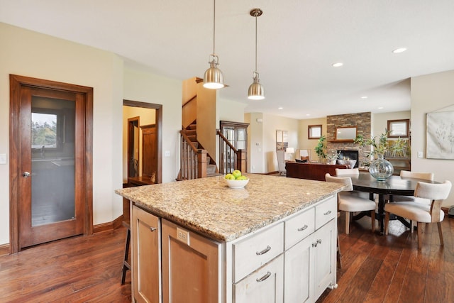 kitchen featuring white cabinetry, dark hardwood / wood-style floors, pendant lighting, a fireplace, and a kitchen island