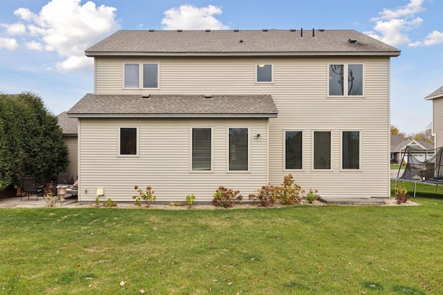 back of house with a yard, a patio, and a trampoline