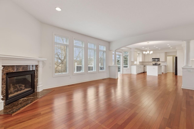 unfurnished living room with hardwood / wood-style floors, a high end fireplace, and a chandelier