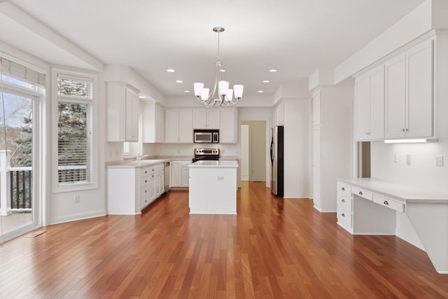 kitchen with dark hardwood / wood-style flooring, stainless steel appliances, a kitchen island, pendant lighting, and white cabinetry