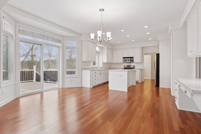 kitchen featuring appliances with stainless steel finishes, a center island, white cabinetry, and hanging light fixtures