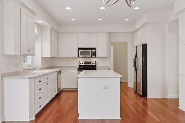 kitchen with sink, a kitchen island, dark hardwood / wood-style flooring, white cabinets, and appliances with stainless steel finishes