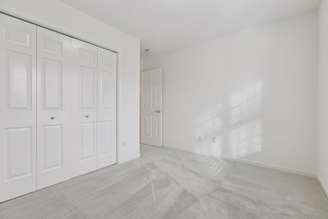 unfurnished bedroom with light carpet and a closet