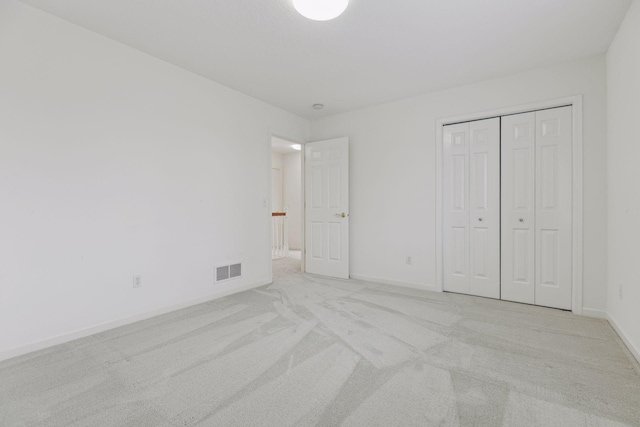 unfurnished bedroom featuring light carpet and a closet