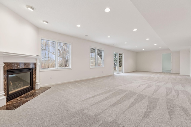 unfurnished living room featuring a high end fireplace and light colored carpet