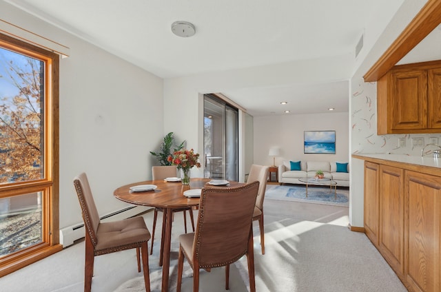 dining space with a baseboard radiator, plenty of natural light, and light carpet