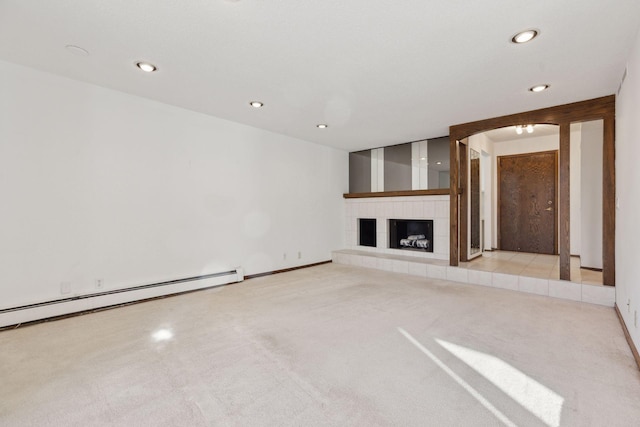 unfurnished living room with a baseboard radiator, a tiled fireplace, and light colored carpet