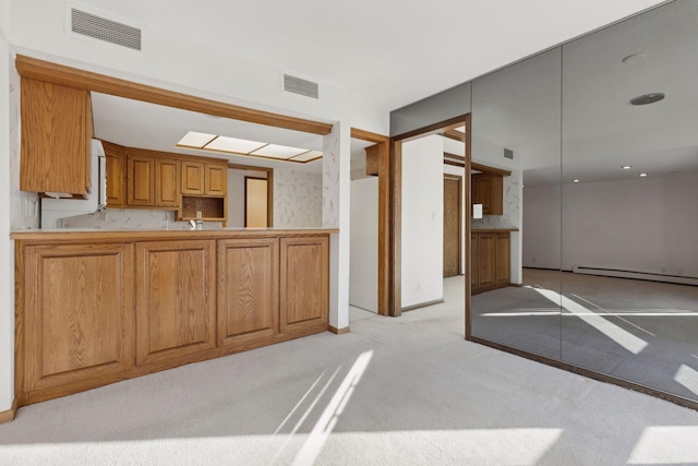 kitchen featuring baseboard heating, kitchen peninsula, sink, and light carpet