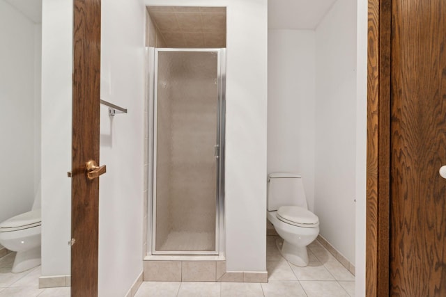 bathroom with tile patterned flooring, a shower with shower door, and toilet