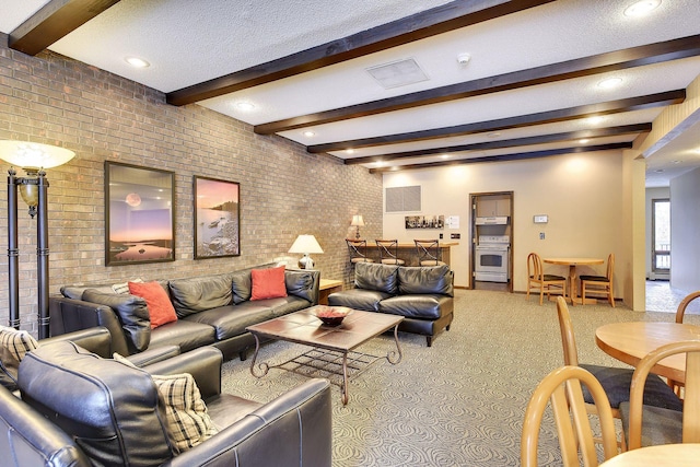 living room with carpet flooring, beam ceiling, a textured ceiling, and brick wall