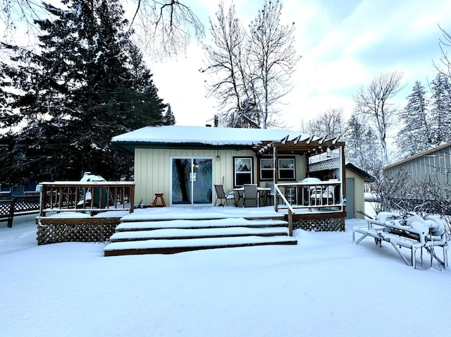 snow covered house featuring a pergola and a wooden deck