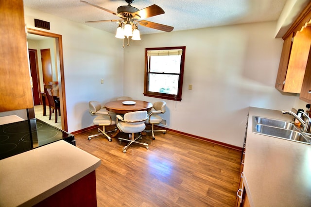 dining space featuring a textured ceiling, ceiling fan, hardwood / wood-style floors, and sink