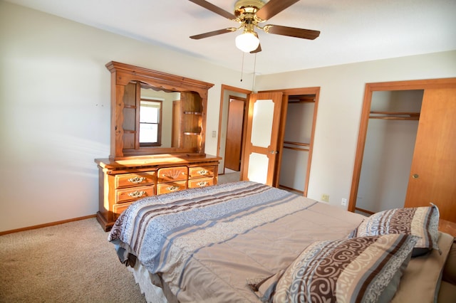 carpeted bedroom with ceiling fan and multiple closets