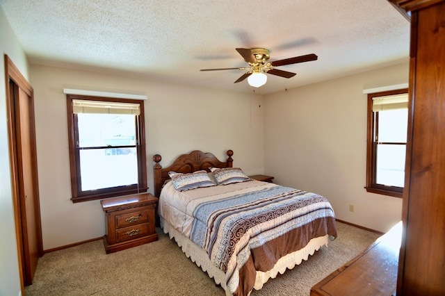 carpeted bedroom featuring ceiling fan and a textured ceiling